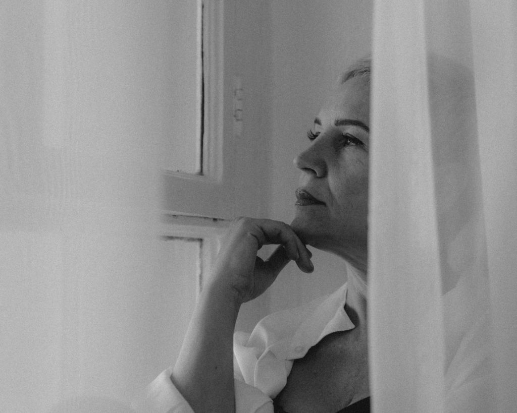 Frau in Schwarz-Weiß hinter Gardinen