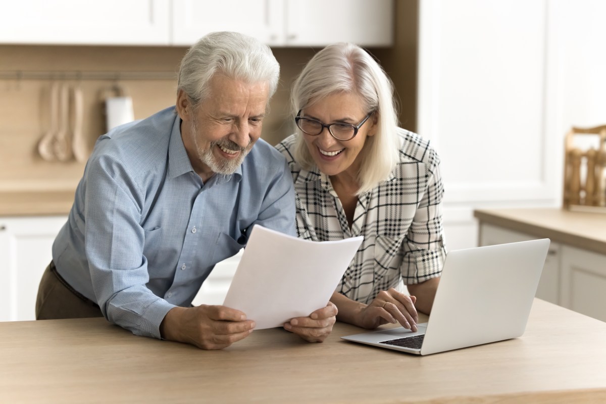 Ein Rentner-Ehepaar schaut sich ein Dokument an.