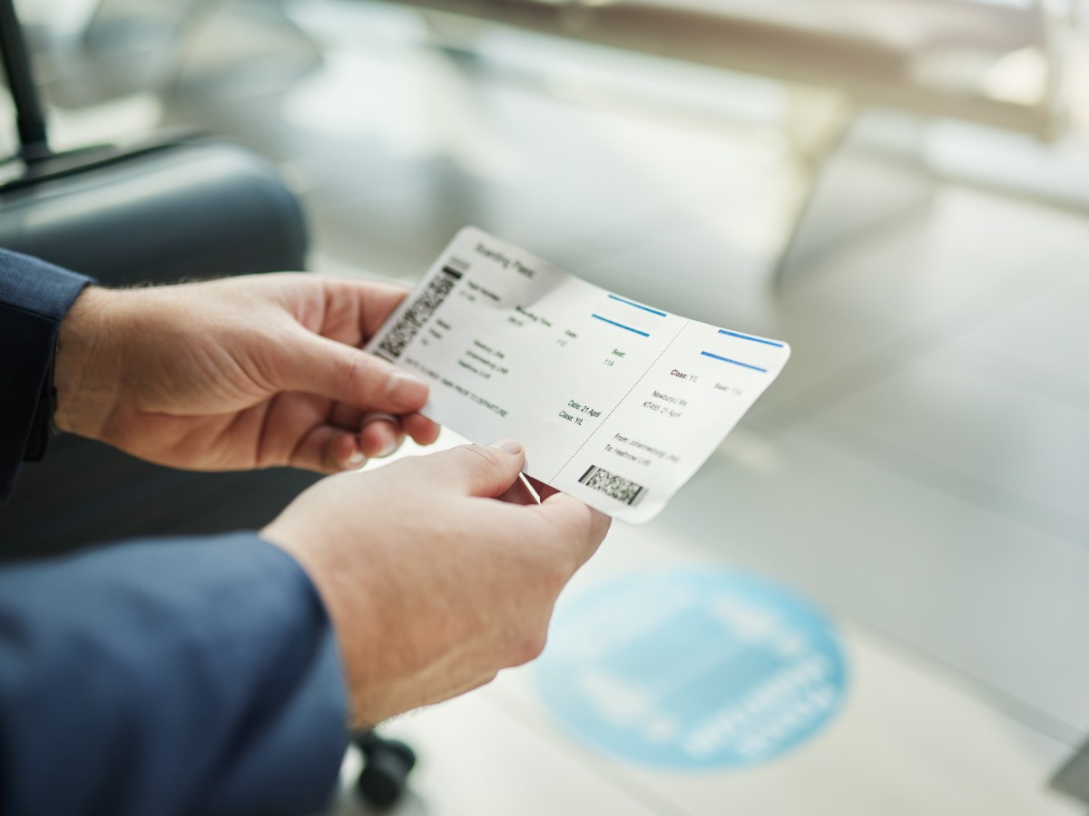 Eine Person hÃ¤lt ein Flugticket in der Hand.