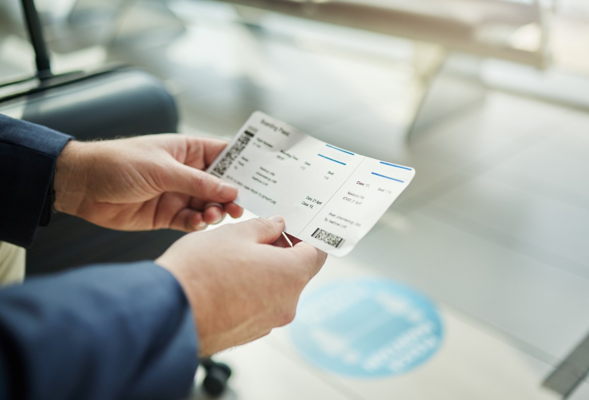 Eine Person hält ein Flugticket in der Hand.