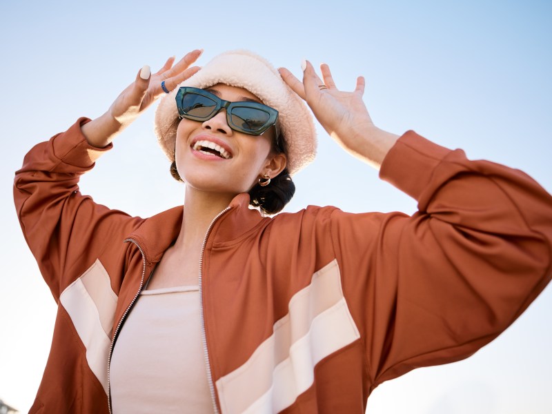 Junge Frau mit Sonnenbrille vor blauem Himmel