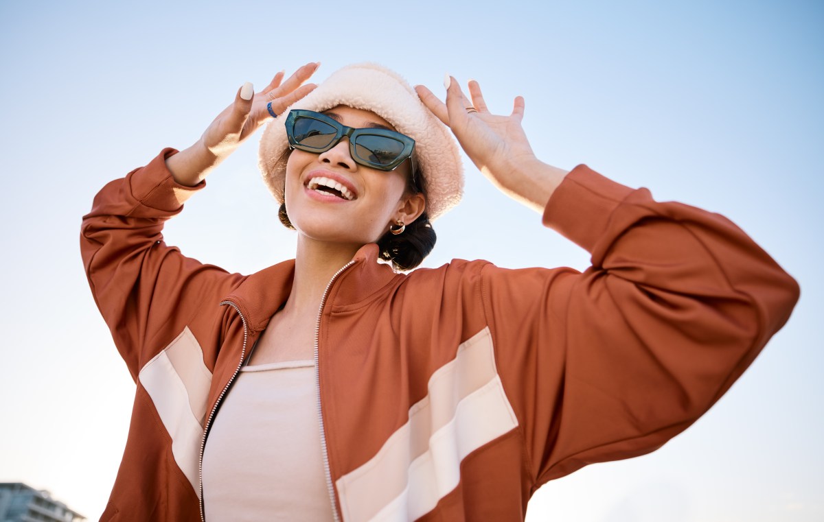 Junge Frau mit Sonnenbrille vor blauem Himmel