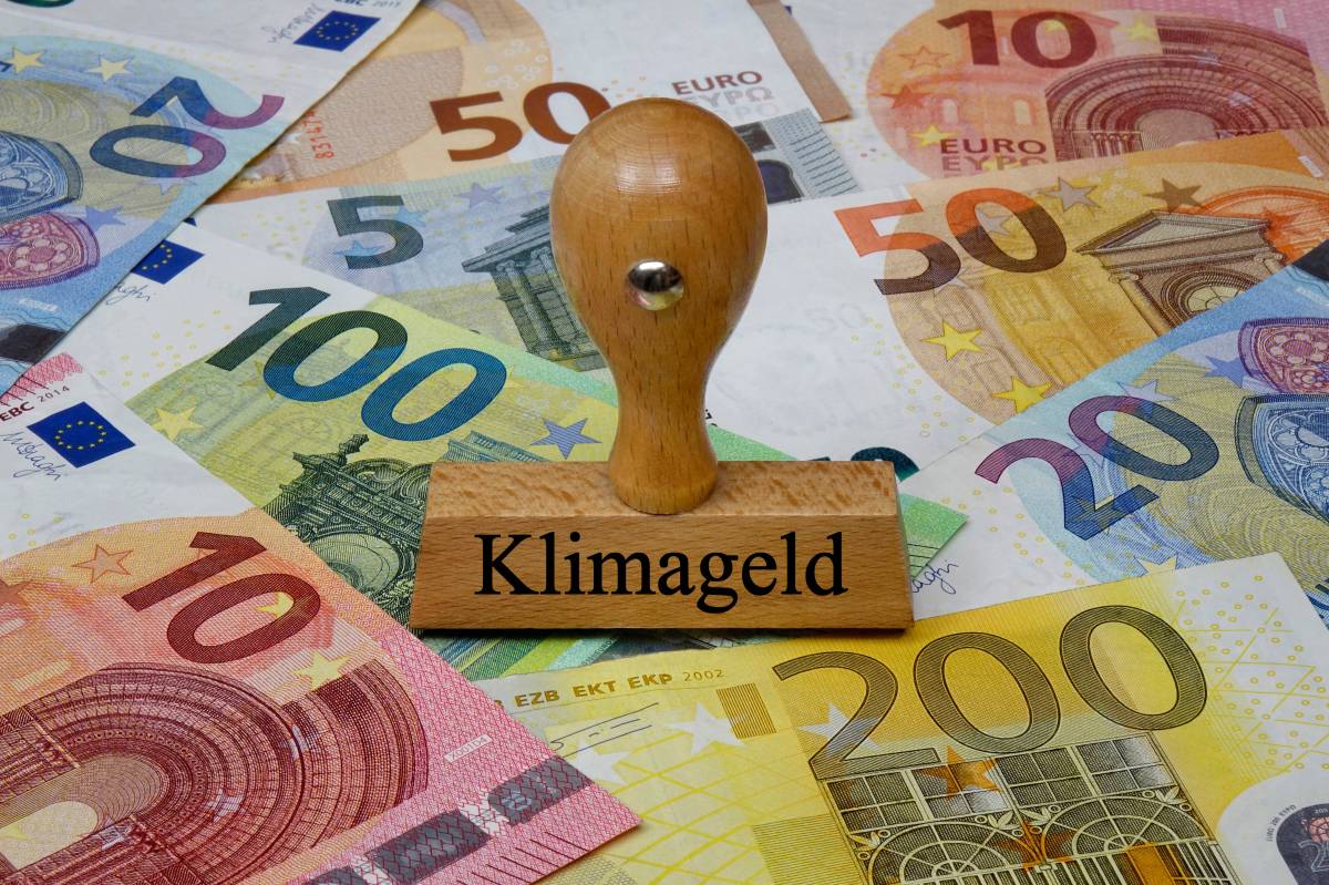 Ein Stempel mit der Aufschrift "Klimageld" liegt auch Euro-Scheinen.