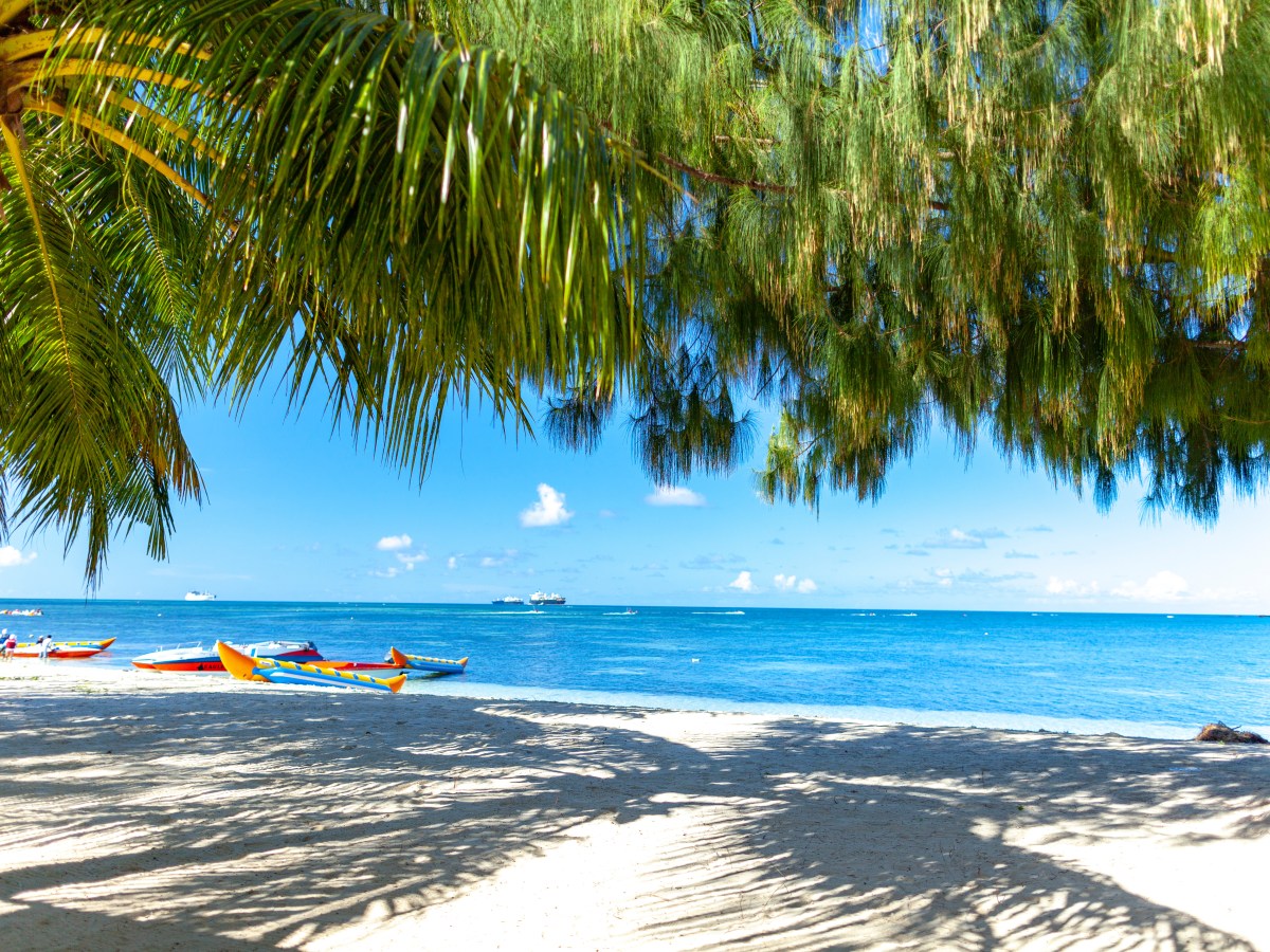 Ein weiÃŸer Sandstrand mit Palmen und blauem Wasser.