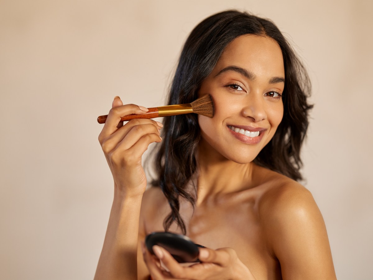 Frau trÃ¤gt Contouring mit einem Pinsel auf ihre Wangen auf.