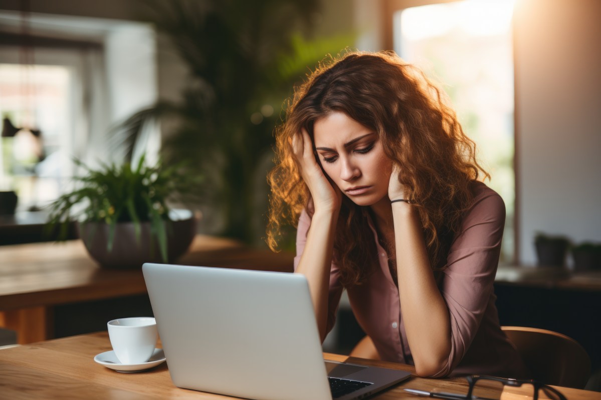 Eine Frau sitzt erschöpft vor ihrem Laptop.