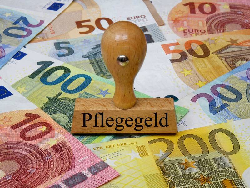 Ein Stempel mit der Aufschrift "Pflegegeld" steht auf Geldscheinen.