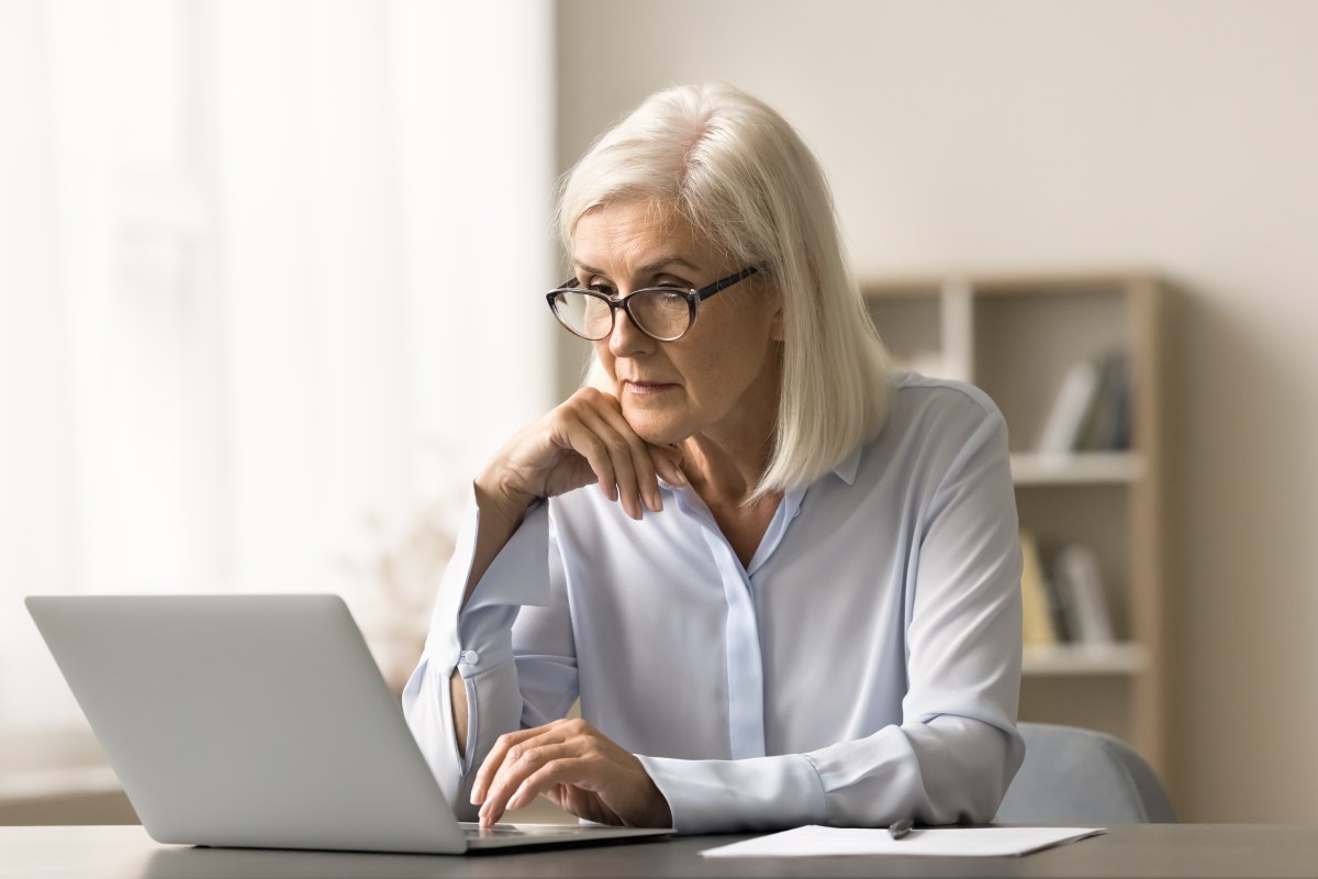 Eine Ã¤ltere Dame sitzt vor dem Laptop und arbeitet.