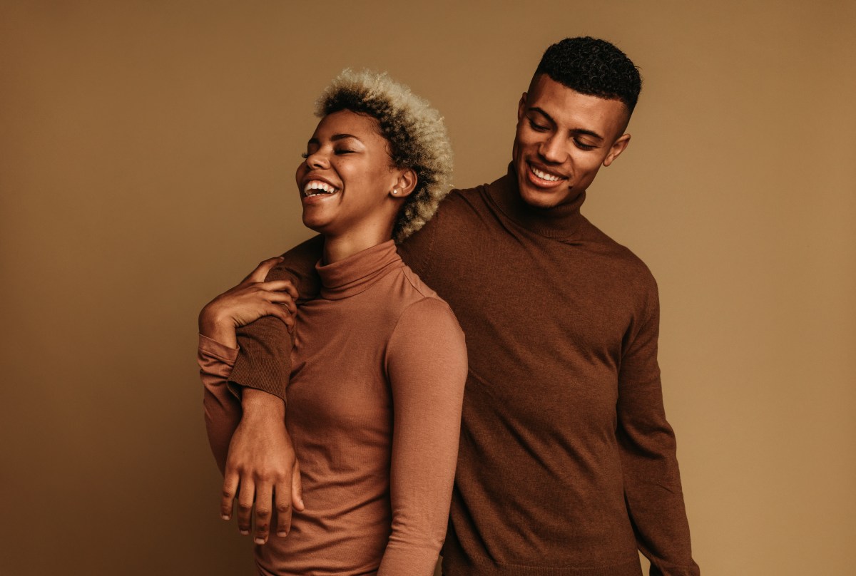Frau und Mann tragen braune Kleidung und lachen gemeinsam.