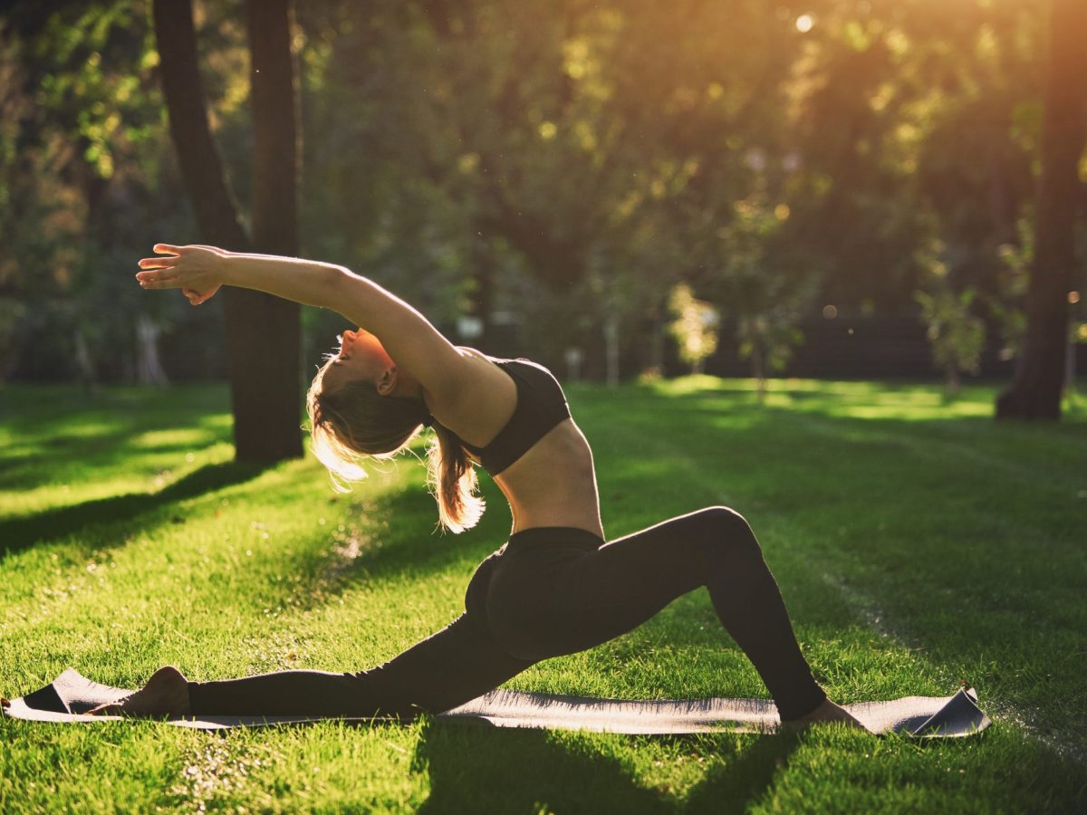 Eine Frau macht im Park Yoga.