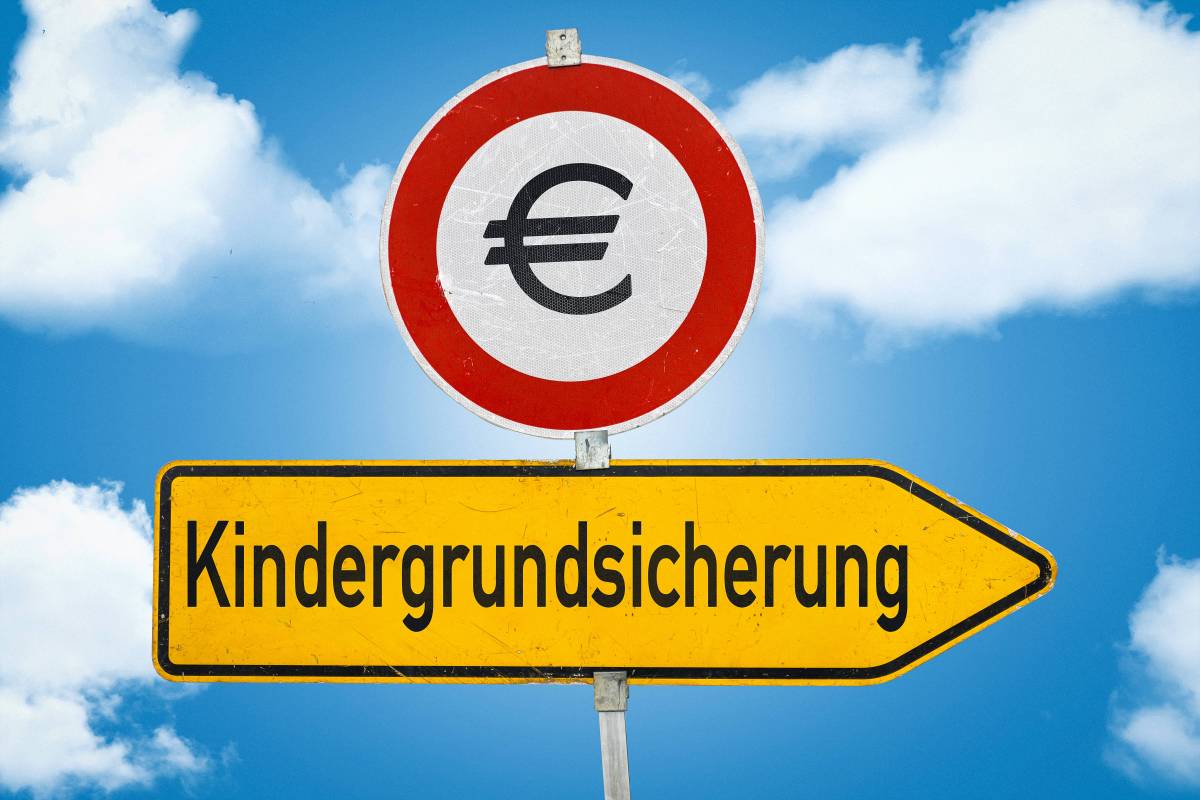 Auf einem gelben Schild steht das Wort "Kindergrundsicherung". Darüber ist ein rundes Schild mit einem Euro-Zeichen.