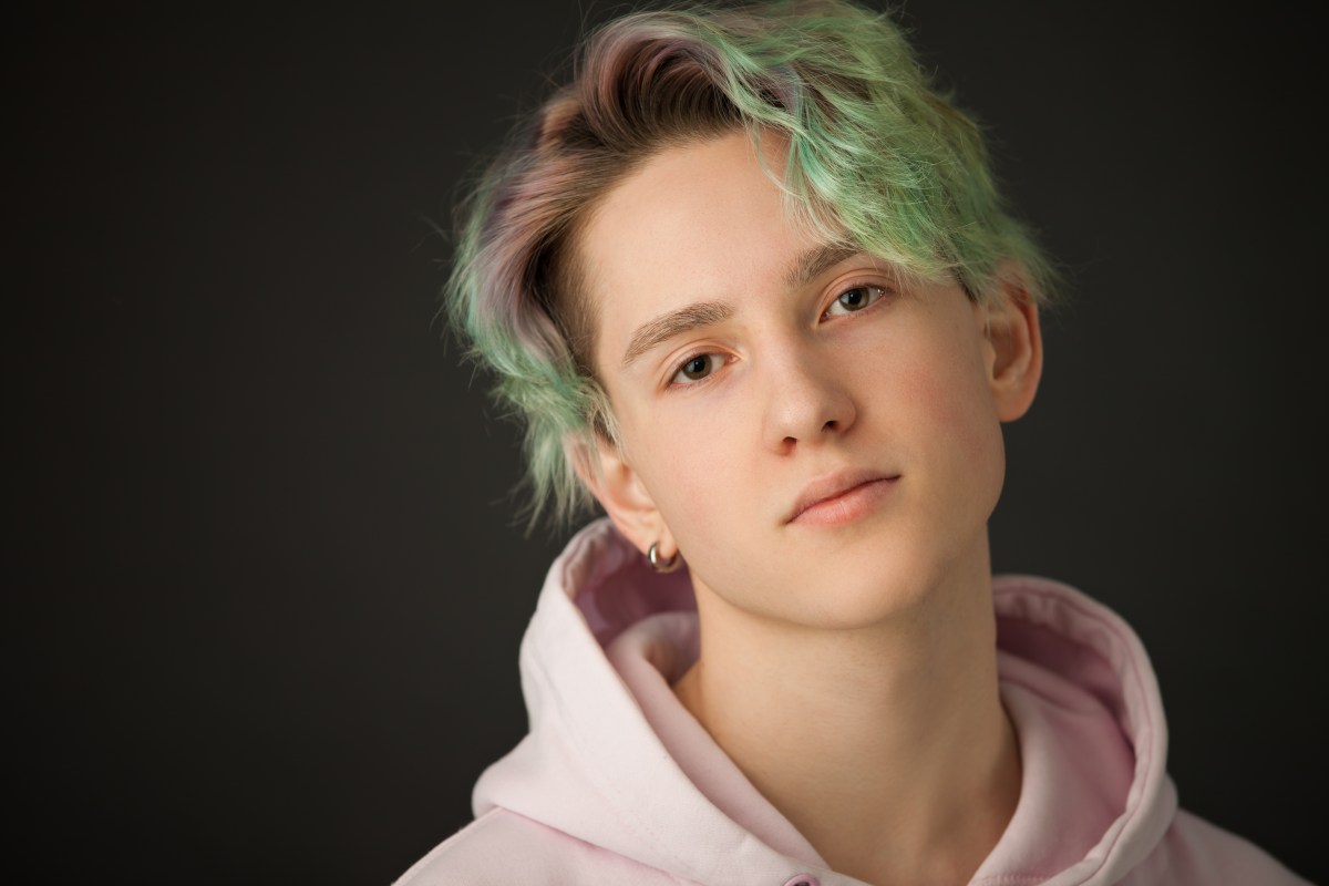 Studio-Porträt eines Teenagers mit grünen Haaren auf schwarzem Hintergrund