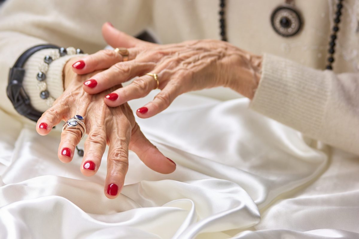 Hände einer alten Frau mit roten Fingernägeln