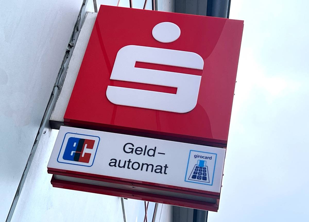 Ein Logo der Sparkasse hängt an einem Gebäude.