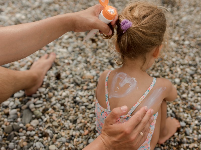 Kind wird mit Sonnencreme eingecremt