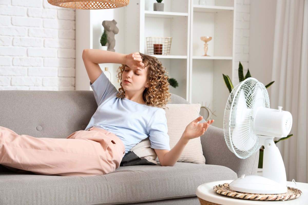 Eine Frau liegt auf dem Sofa. Ihr ist warm. Ein Ventilator ist auf sie gerichtet.