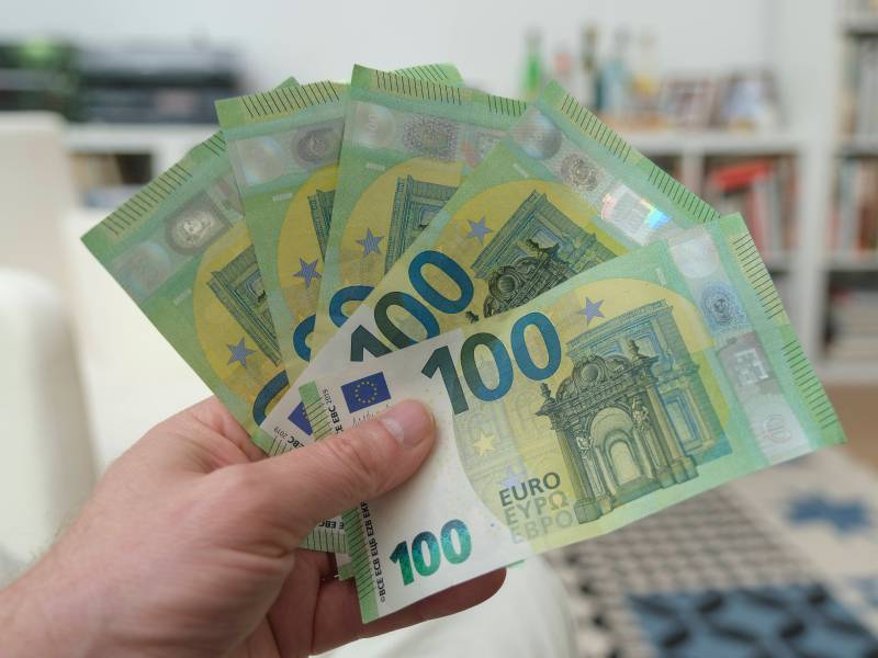 Eine Person hÃ¤lt fÃ¼nf 100-Euro-Scheine in der Hand.