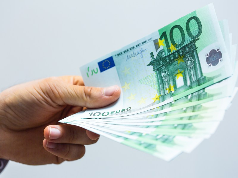 Eine Person hält mehrere 100-Euro-Scheine in der Hand.