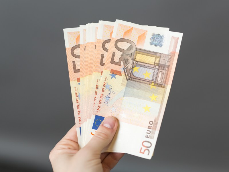 Eine Person hÃ¤lt mehrere 50-Euro-Scheine in der Hand.