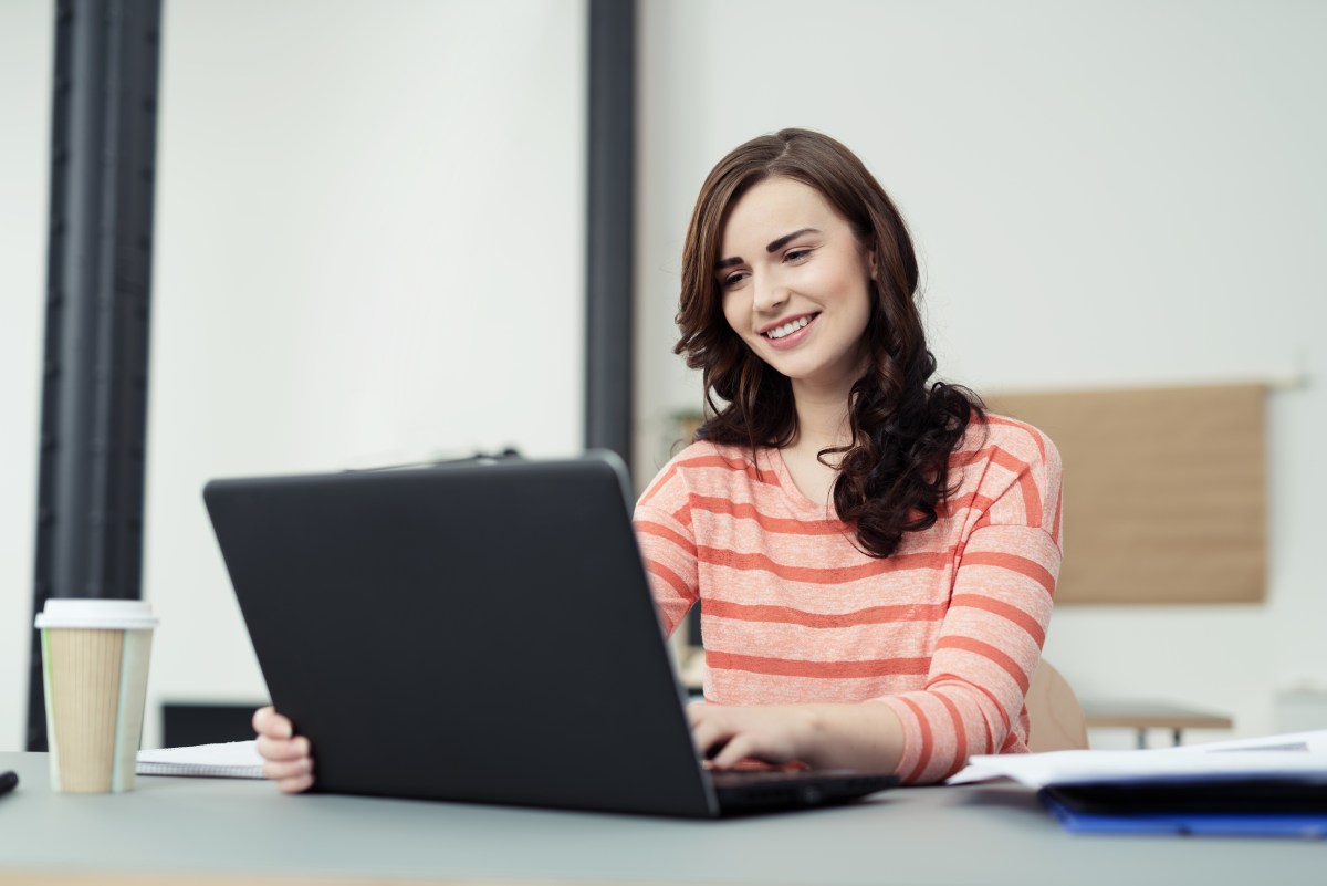 Eine Frau sitzt am Laptop und arbeitet.