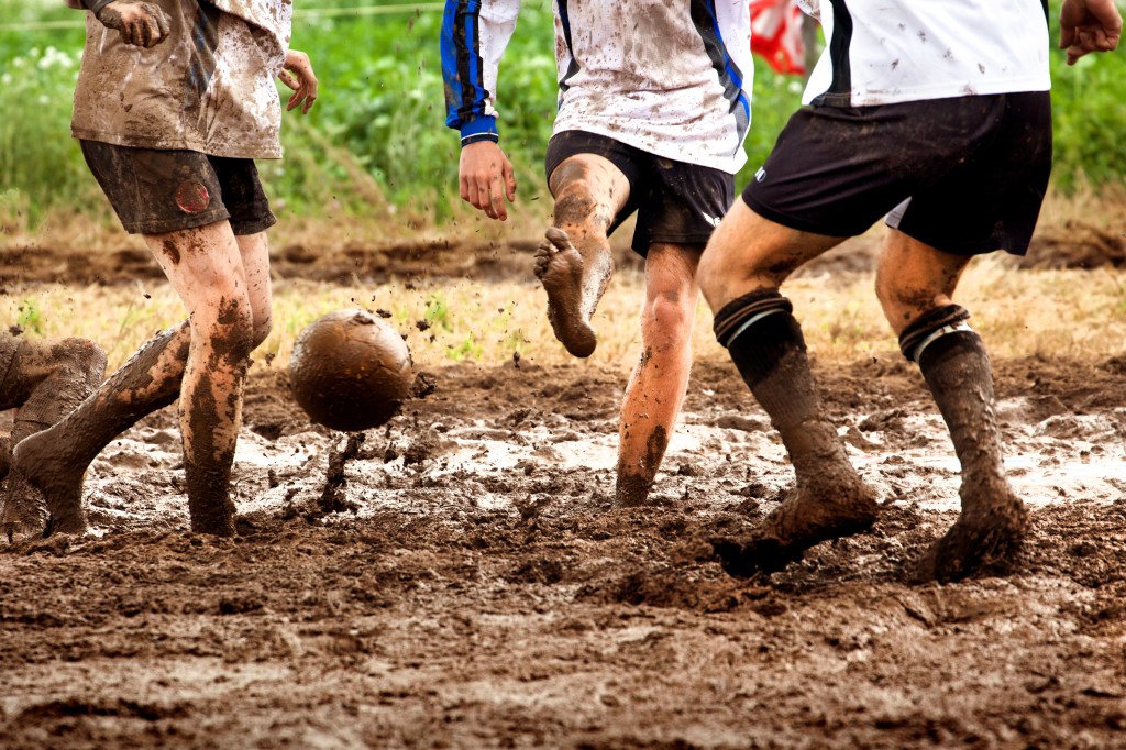 Jungs spielen im Matsch Fußball