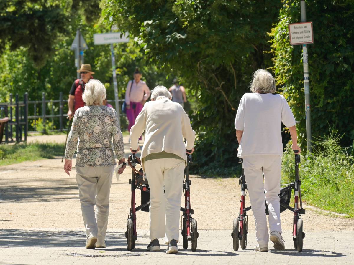 Eine Gruppe von Seniorinnen. Zwei gehen am Rollator.