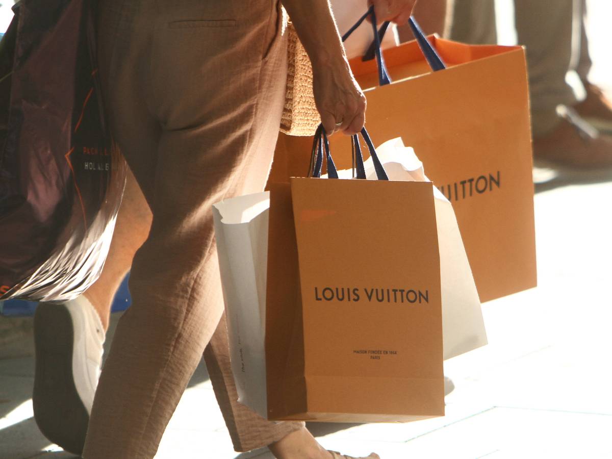 Zwei Personen tragen TÃ¼ten der Marke Louis Vuitton.