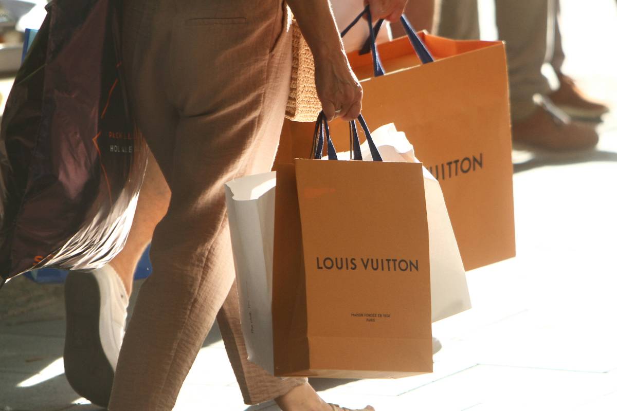 Zwei Personen tragen TÃ¼ten der Marke Louis Vuitton.