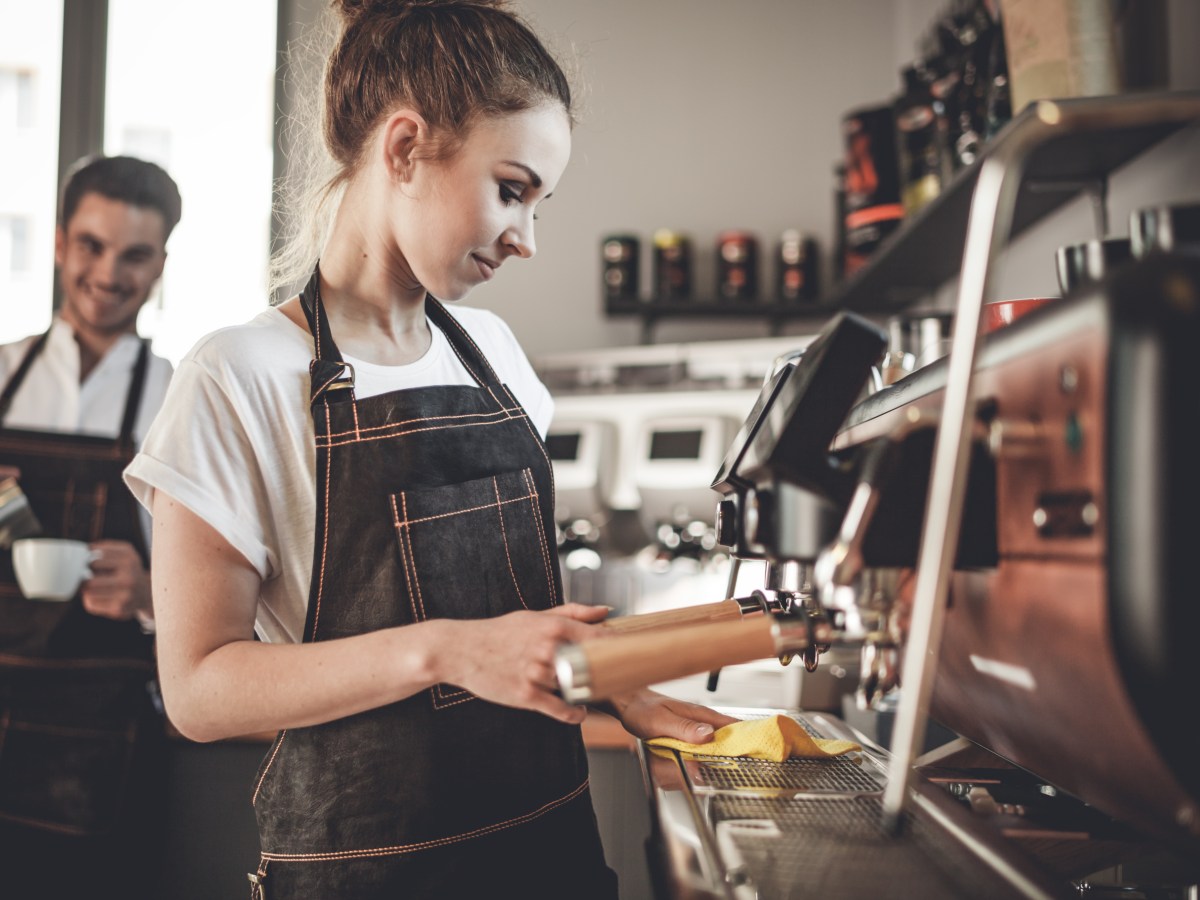 Eine Frau bereitet einen Kaffee an der Kaffeemaschine vor.