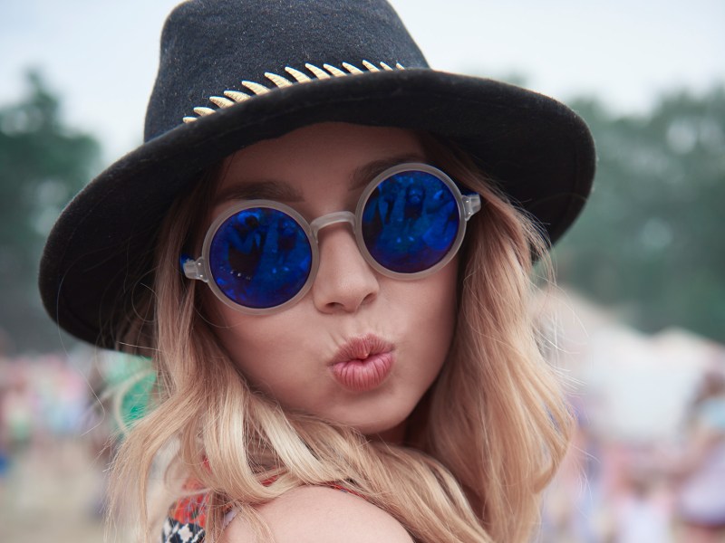 Frau mit Hut auf einem Festival macht Duckface