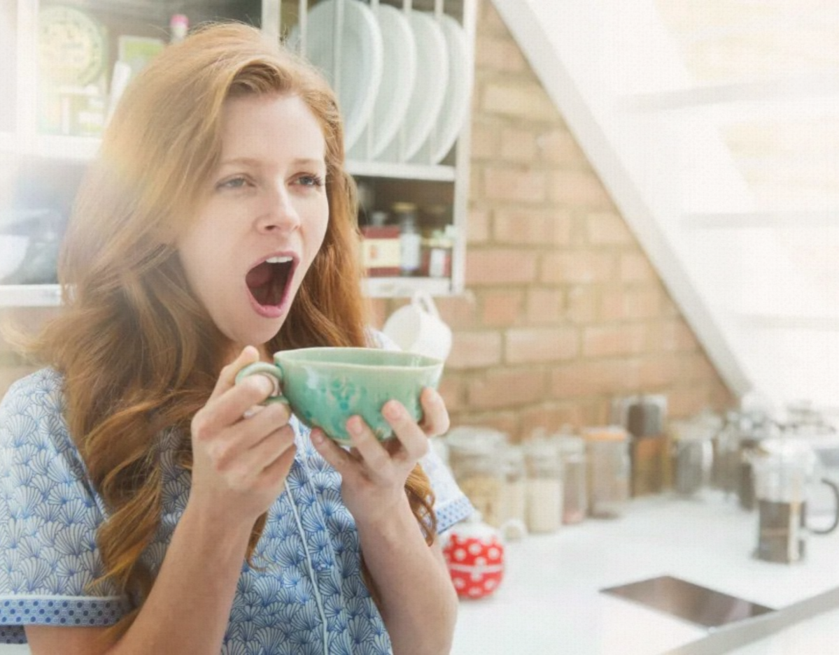 Frau gähnt mit Kaffee