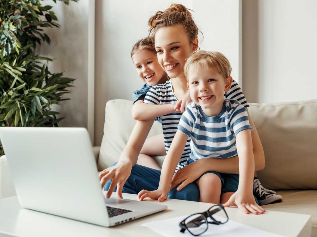 Eine Frau mit zwei kleinen Kindern sitzt vor dem Laptop.