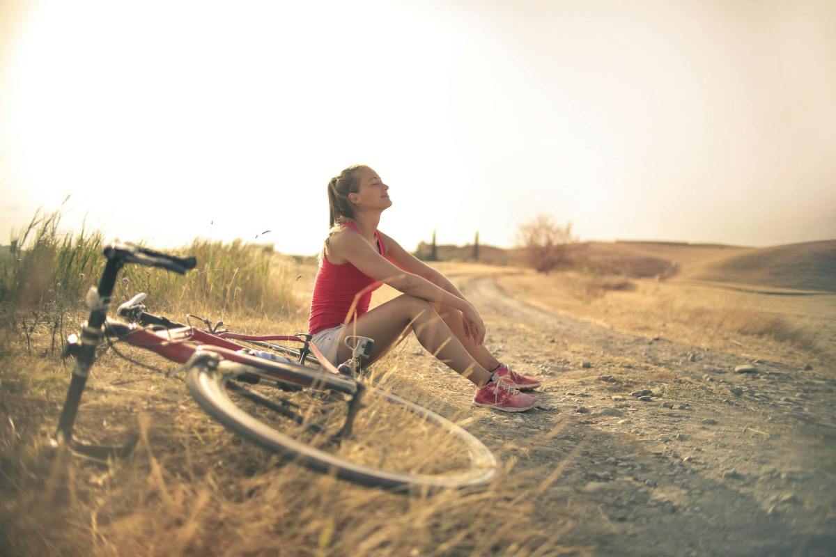 Frau mit Fahrrad macht Pause am Wegrand