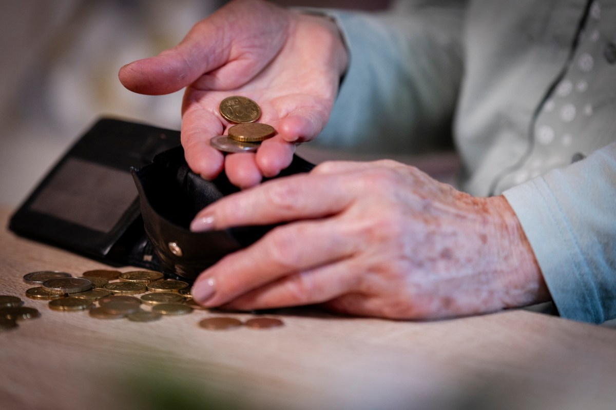 Ã„ltere Person holt MÃ¼nzen aus dem Portemonnaie.