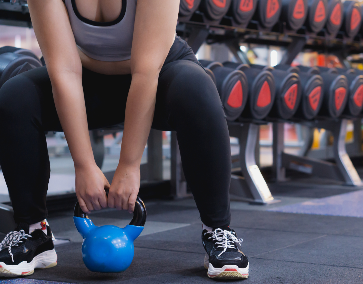 Frau im Fitnessstudio Kniebeuge mit Kettlebell