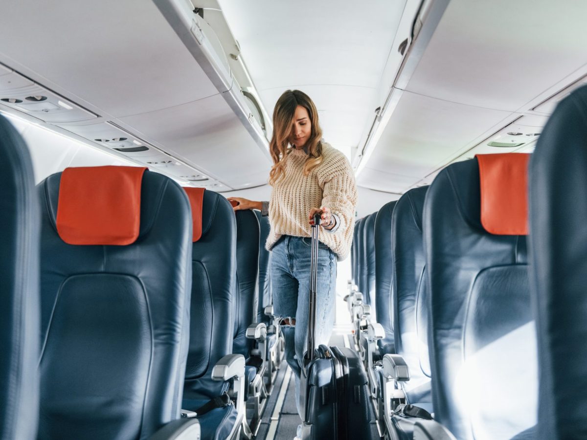 Frau sucht Sitzplatz im Flugzeug