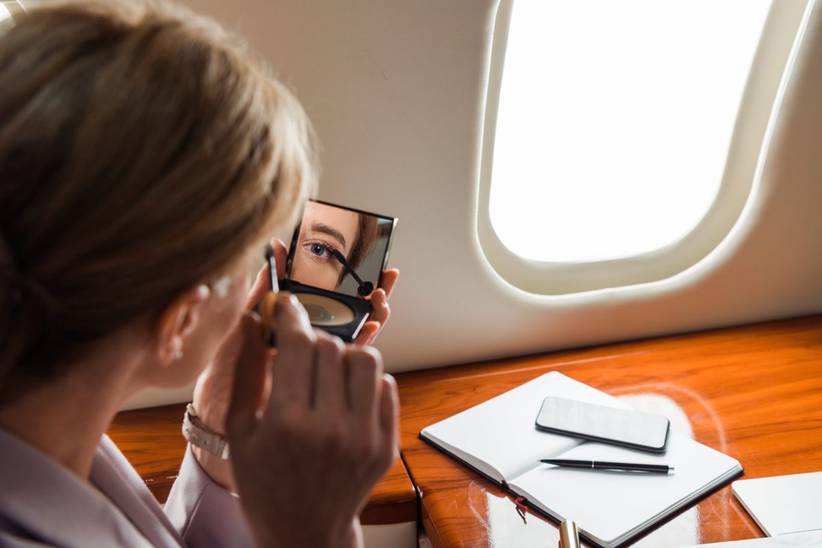 Frau schminkt sich im Flugzeug