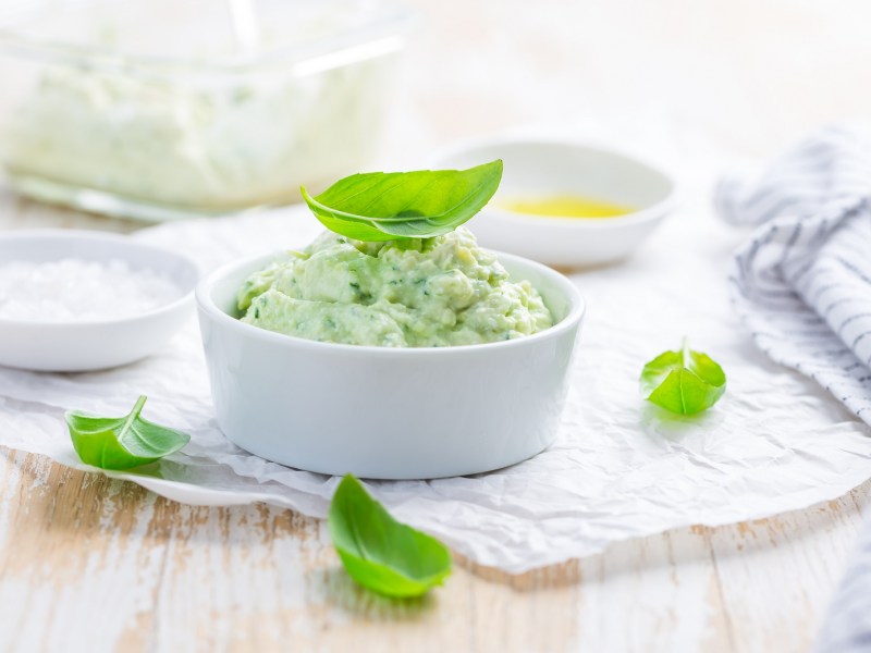 Avocado-Aufstrich mit FrischkÃ¤se in einer weiÃŸen Schale, garniert mit Basilikum.