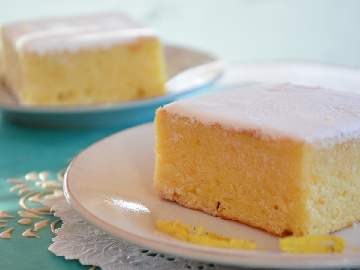 zwei StÃ¼ck Buttermilchkuchen mit Zitrone auf je einem Teller, garniert mit Zuckerguss.