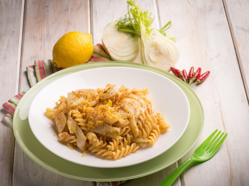 Ein Teller mit Nudeln und Fenchel auf grÃ¼nem Tuch und hellem Untergrund