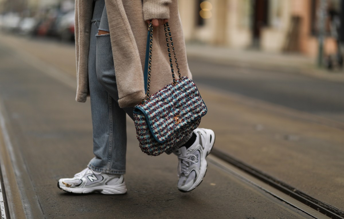 Frau geht in New Balance Sneakern über Straße.