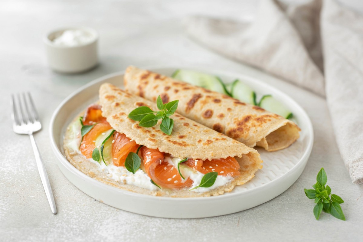 Haferflocken-Pfannkuchen belegt mit Lachs und Frischkäse auf einem Teller.