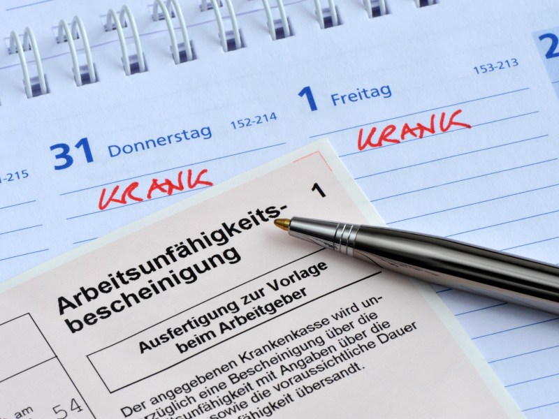 Arbeitsunfähigkeitsbescheinigung und ein Kalender mit Krankmeldung.