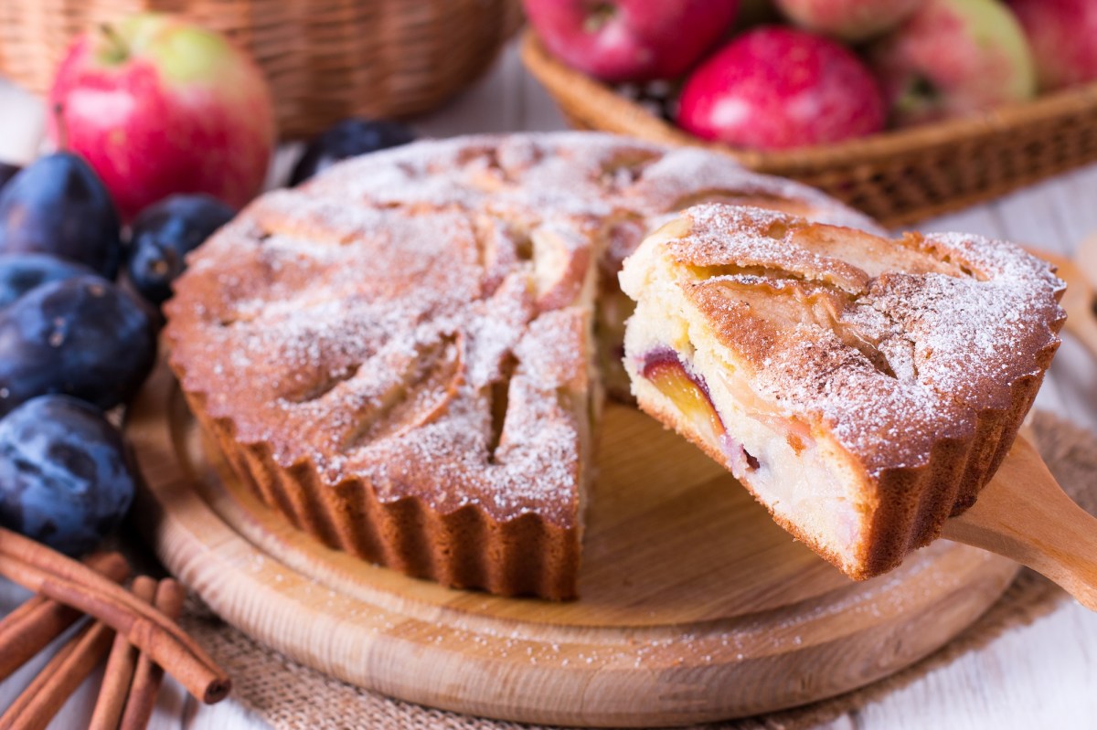 Ein Pflaumen-Apfel-Kuchen auf einem Holzbrett.