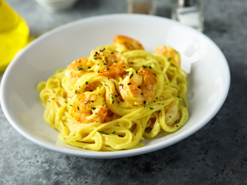 Ein weiÃŸer Teller mit Safran-Pasta mit Garnelen