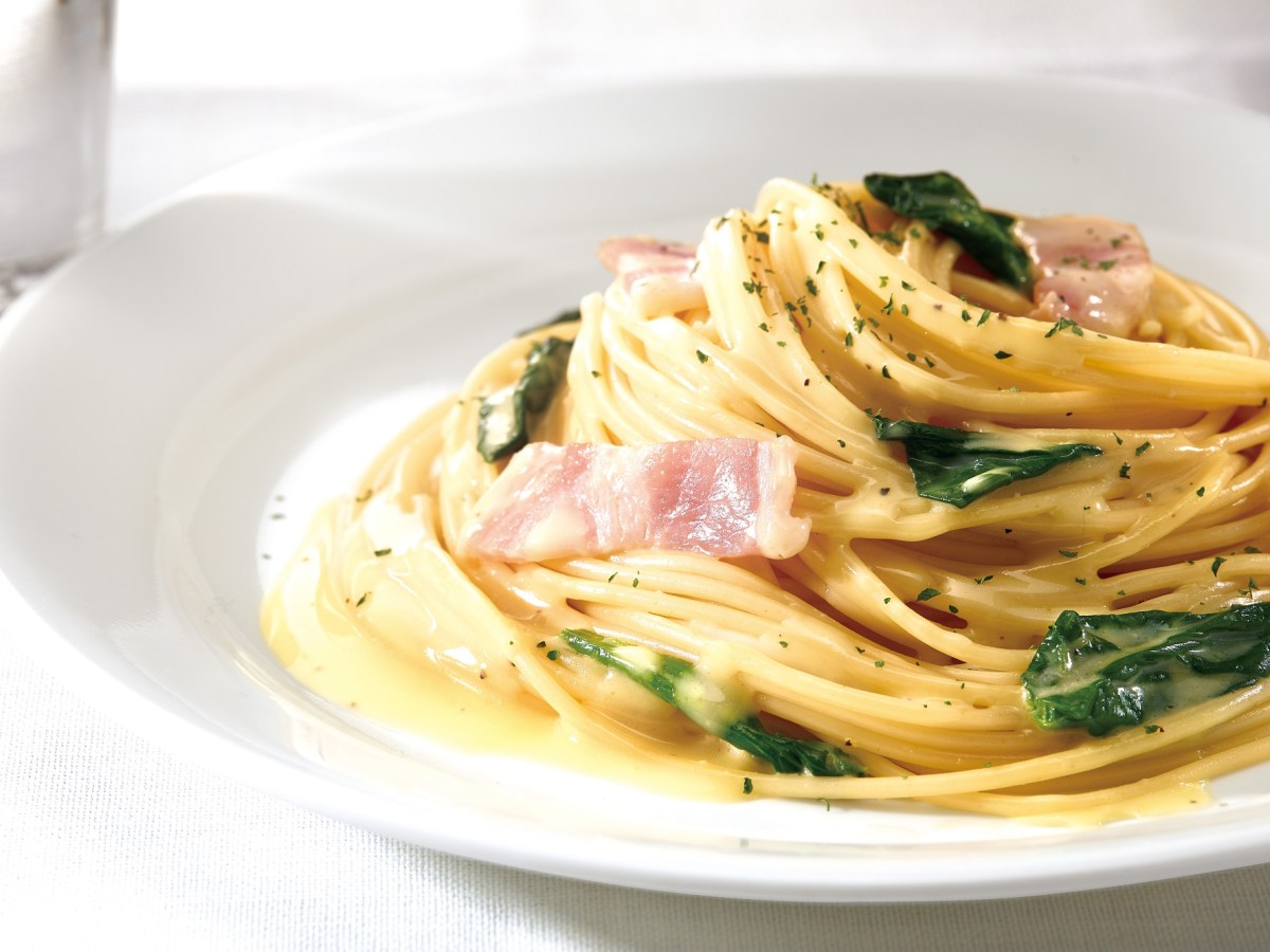 Weißer Teller mit einer Portion Spinat Carbonara