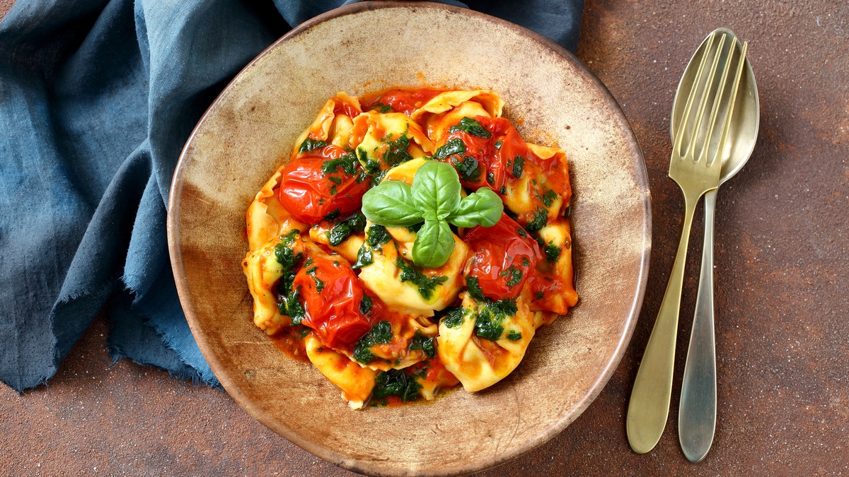 Tortellini al Forno auf einem braunen Teller mit Besteck