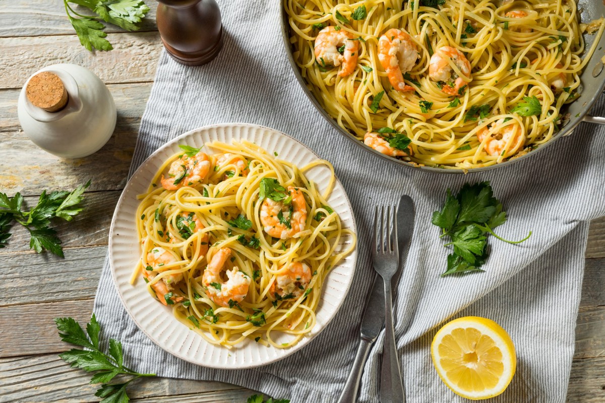 Zitronen-Spaghetti mit Garnelen und Petersilie dekoriert auf einem Teller.