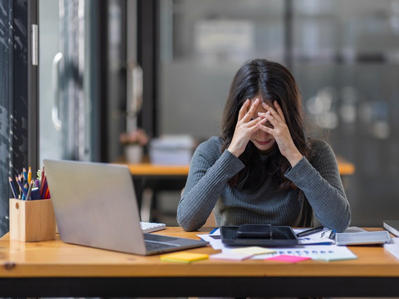 Eine Frau schlÃ¤gt ihre HÃ¤nde vor den Kopf. Sie sitzt im BÃ¼ro.