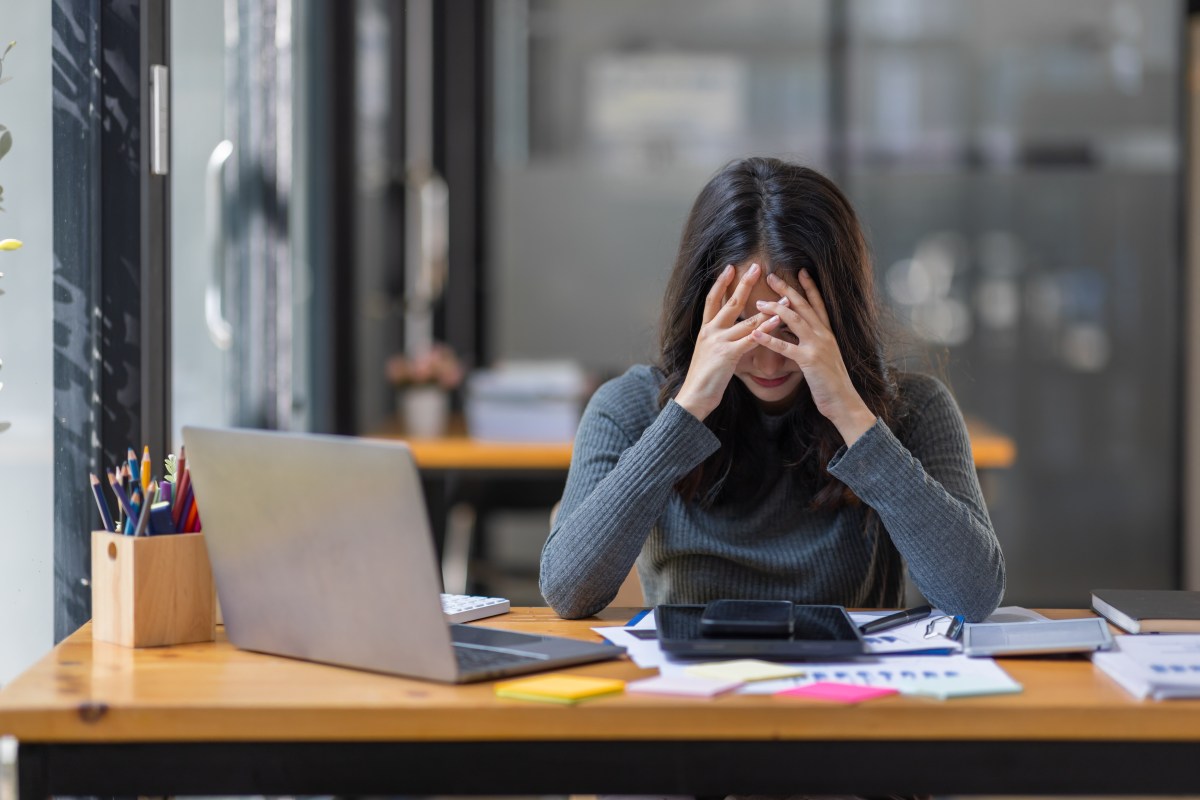 Eine Frau schlÃ¤gt ihre HÃ¤nde vor den Kopf. Sie sitzt im BÃ¼ro.